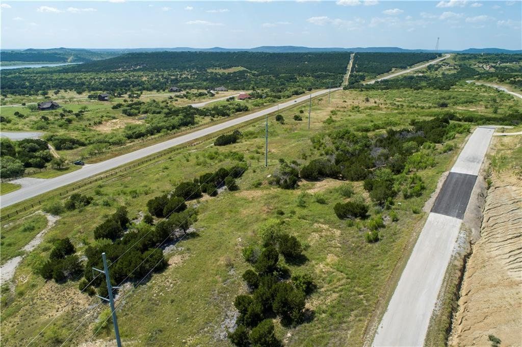 An aerial view of a road going through a grassy field.