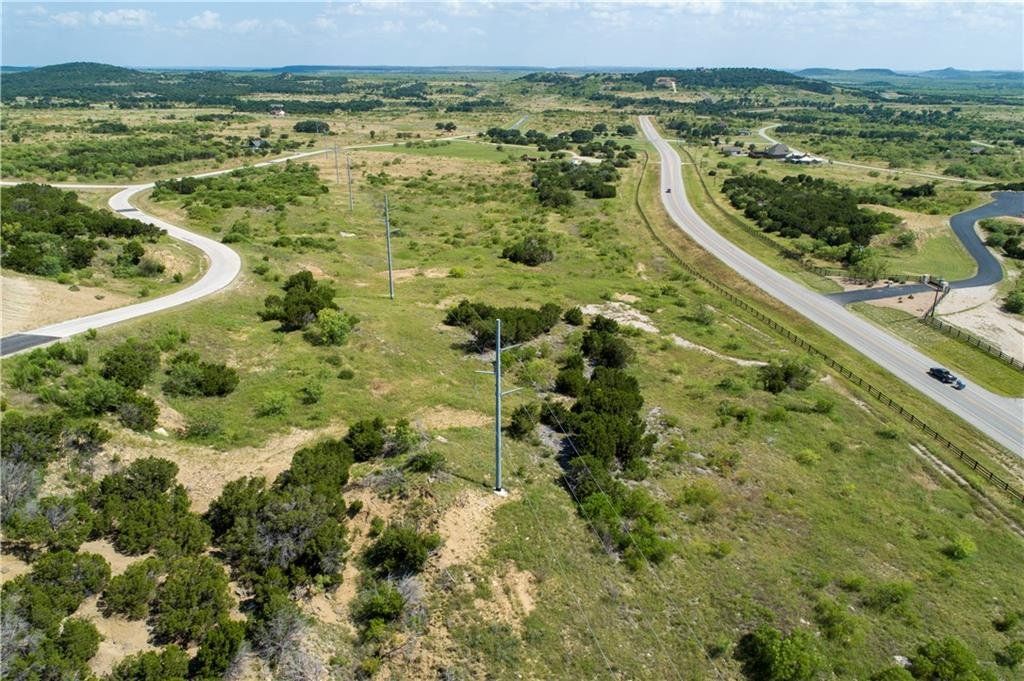 An aerial view of a road going through a grassy field.