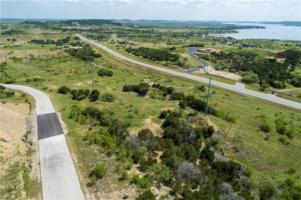 An aerial view of a road going through a grassy field.