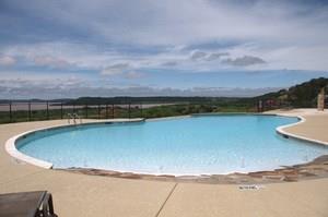 A large swimming pool with a view of a lake on a sunny day.