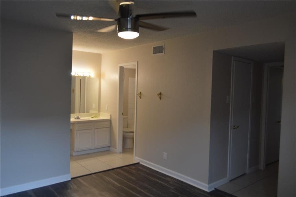 An empty room with a ceiling fan and a bathroom in the background.