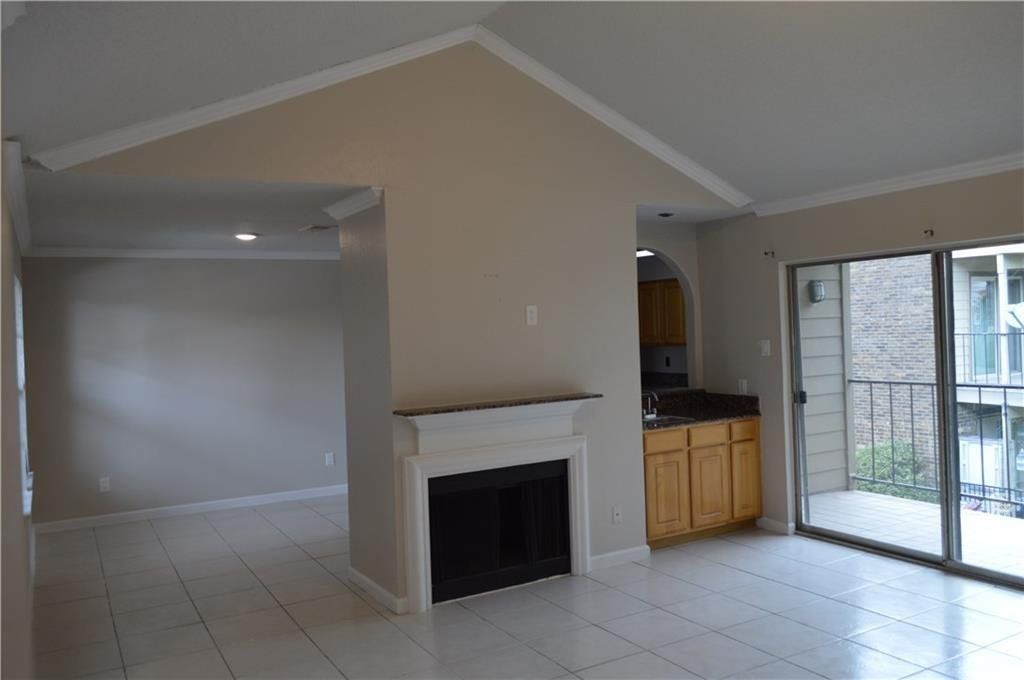 An empty living room with a fireplace and sliding glass doors