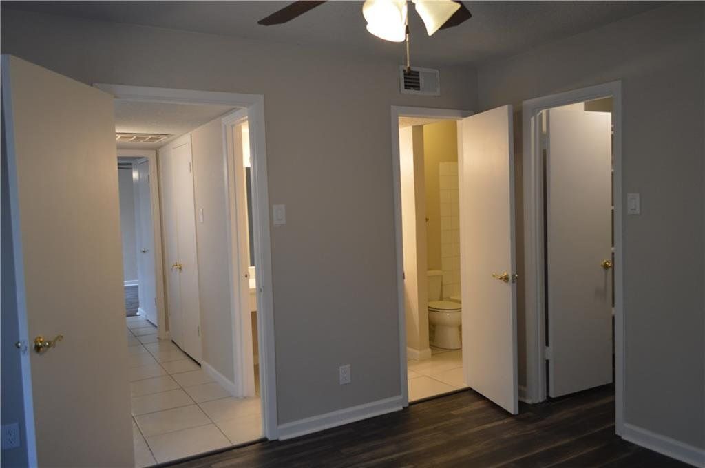 An empty bedroom with a ceiling fan and a bathroom.