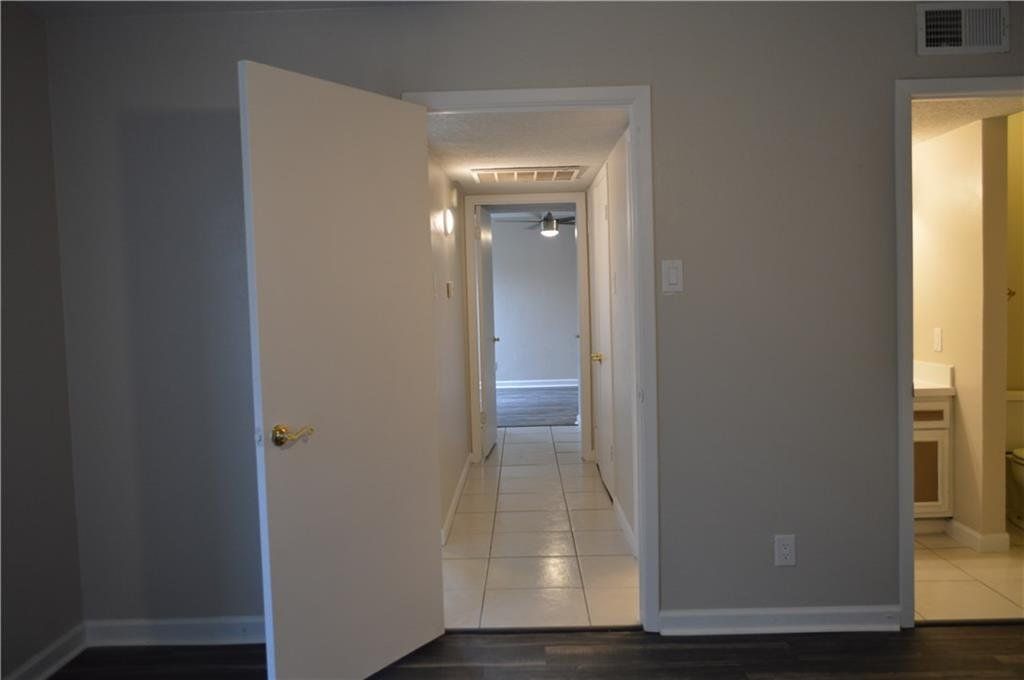 A hallway in a house with a door open leading to a bathroom.