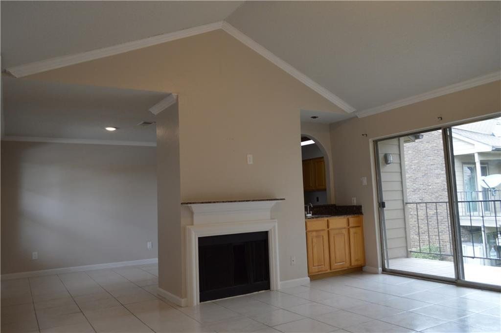 An empty living room with a fireplace and sliding glass doors