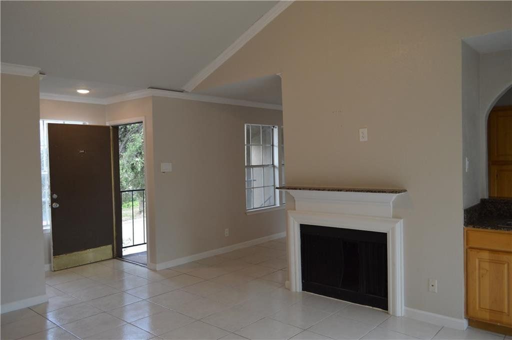 An empty living room with a fireplace and a door.