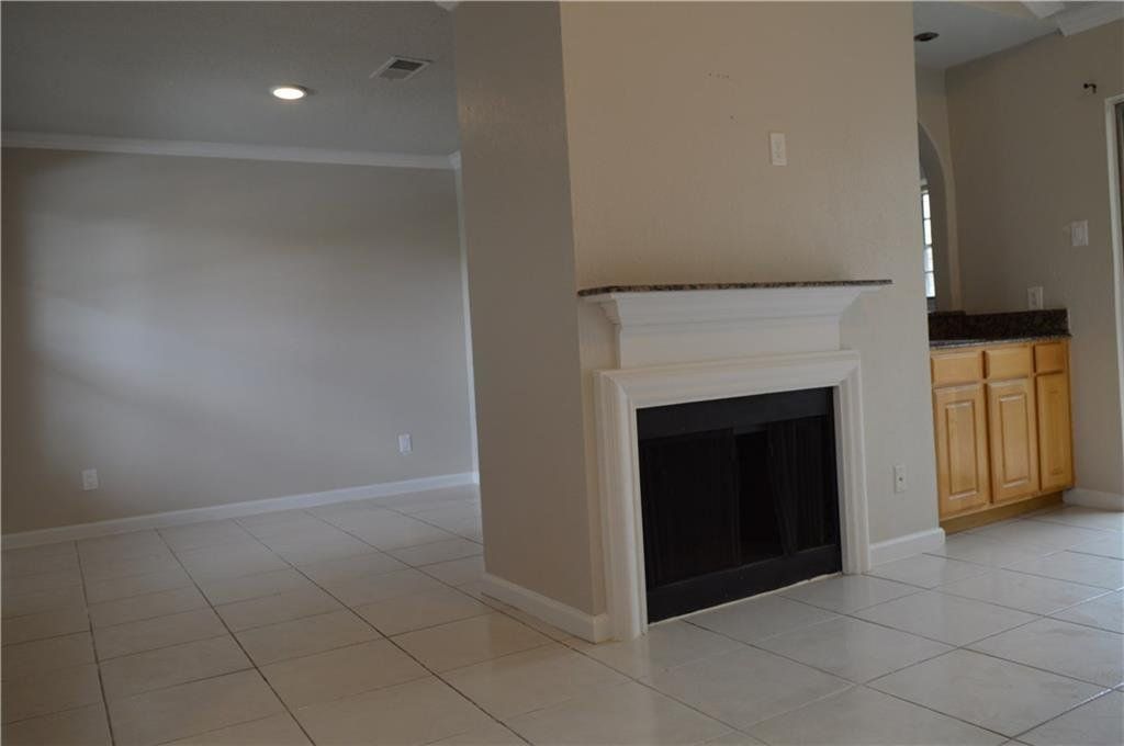 An empty living room with a fireplace and cabinets