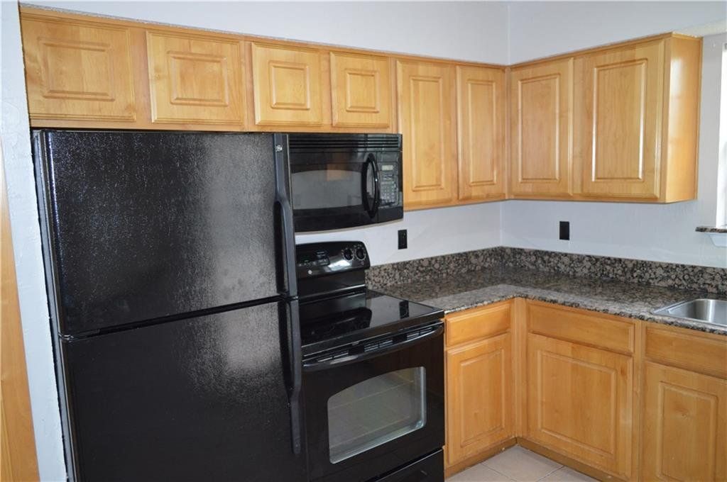 A kitchen with a black refrigerator stove and microwave