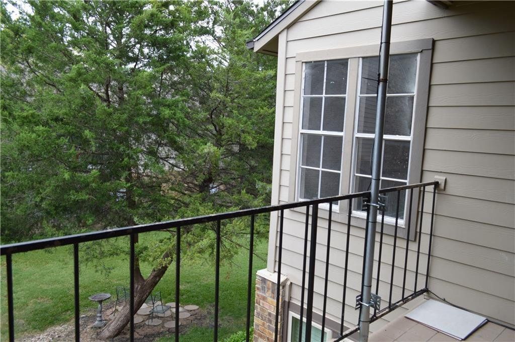 A balcony on the side of a house with trees in the background
