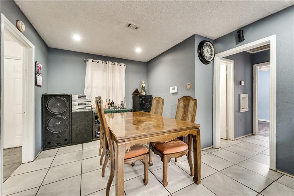 A dining room with a table and chairs and a clock on the wall
