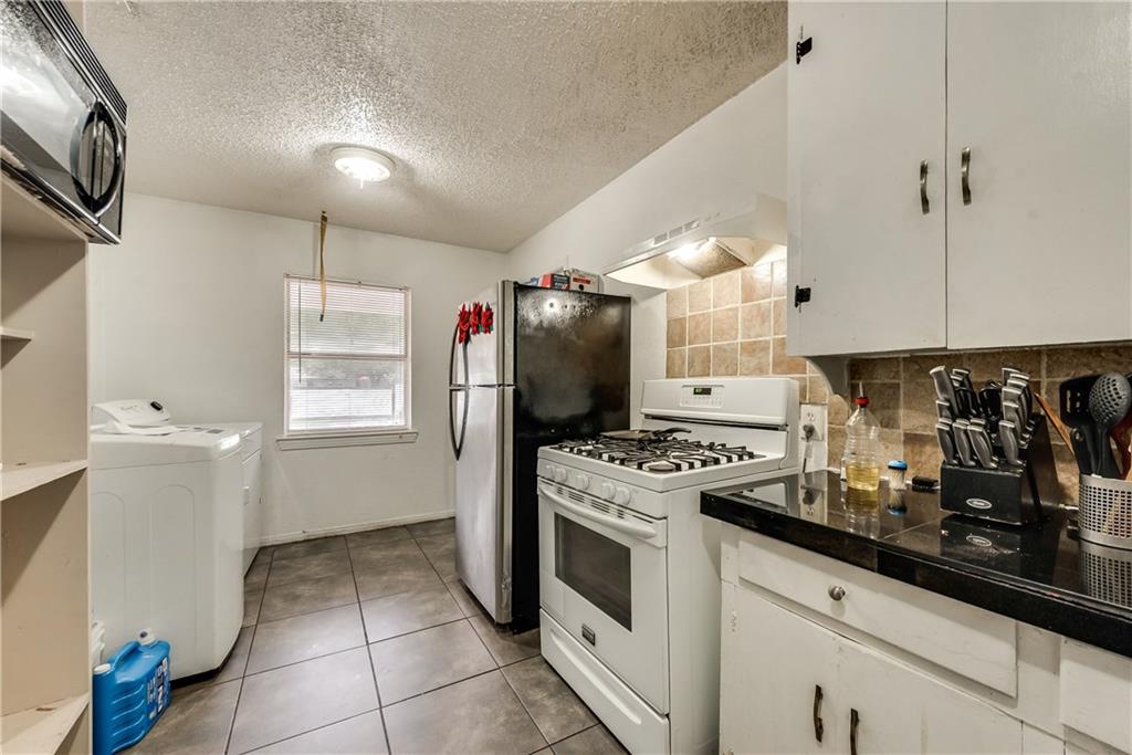 A kitchen with a stove , refrigerator , washer and dryer.