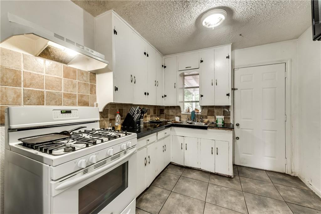 A kitchen with white cabinets and a stove top oven