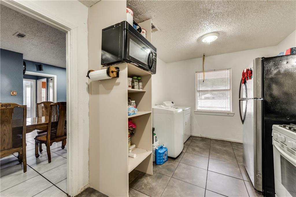A kitchen with a microwave , washer and dryer , refrigerator and stove.