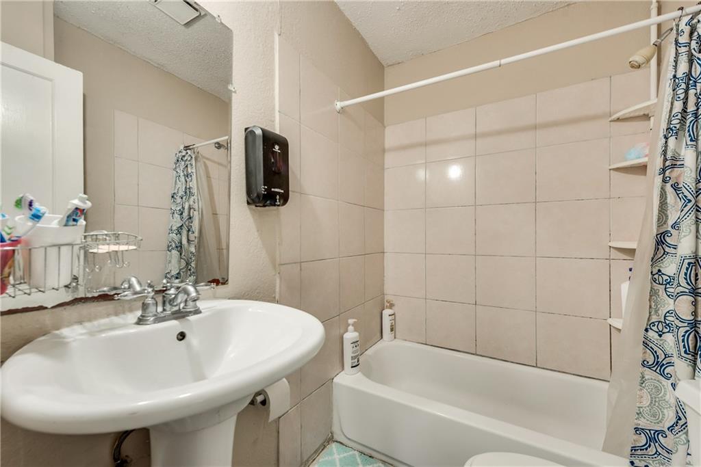 A bathroom with a sink , tub , toilet and mirror.