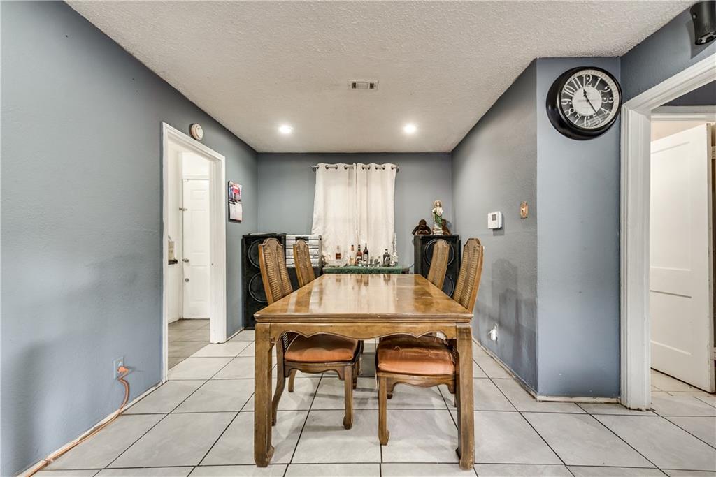 A dining room with a table and chairs and a clock on the wall