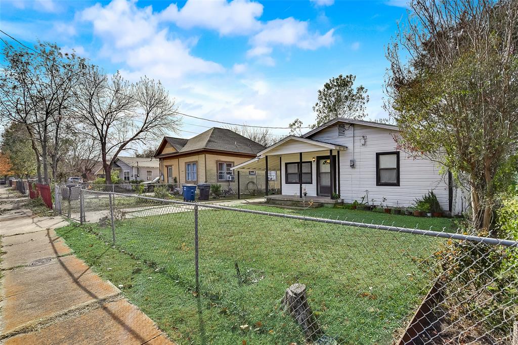 A fenced in yard with a few houses in the background.