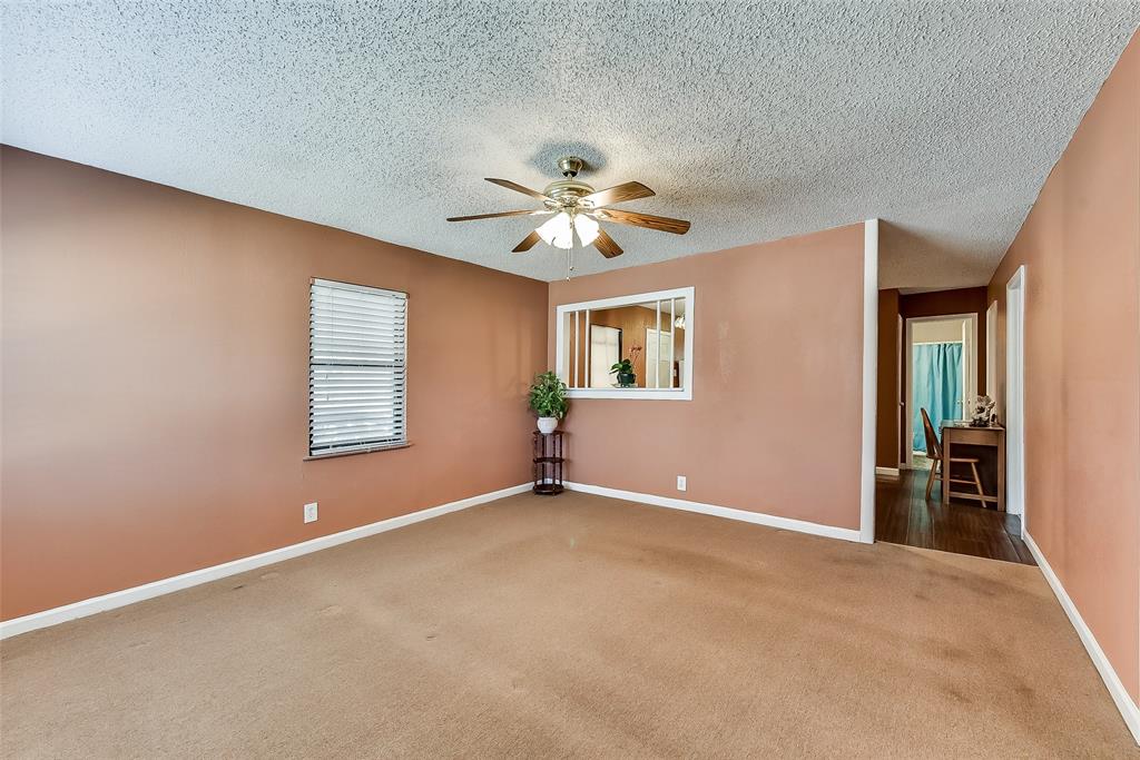 An empty living room with a ceiling fan and a window.