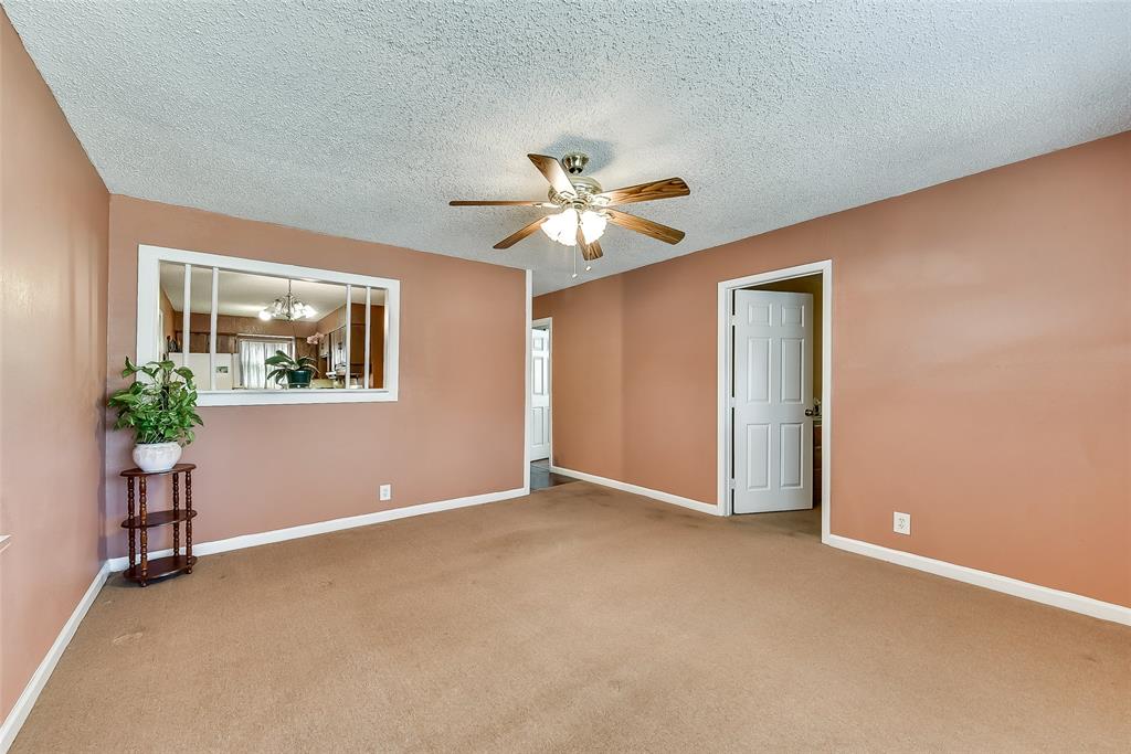 An empty living room with a ceiling fan and a window