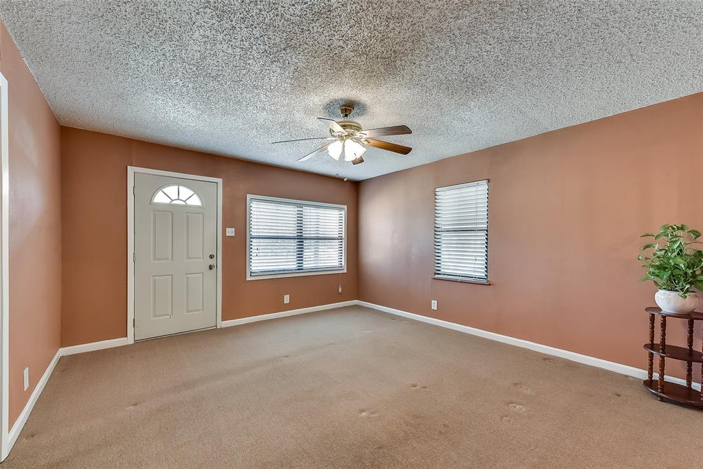 An empty living room with a ceiling fan and a plant.