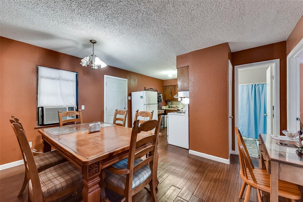 A dining room with a table and chairs and a kitchen in the background.