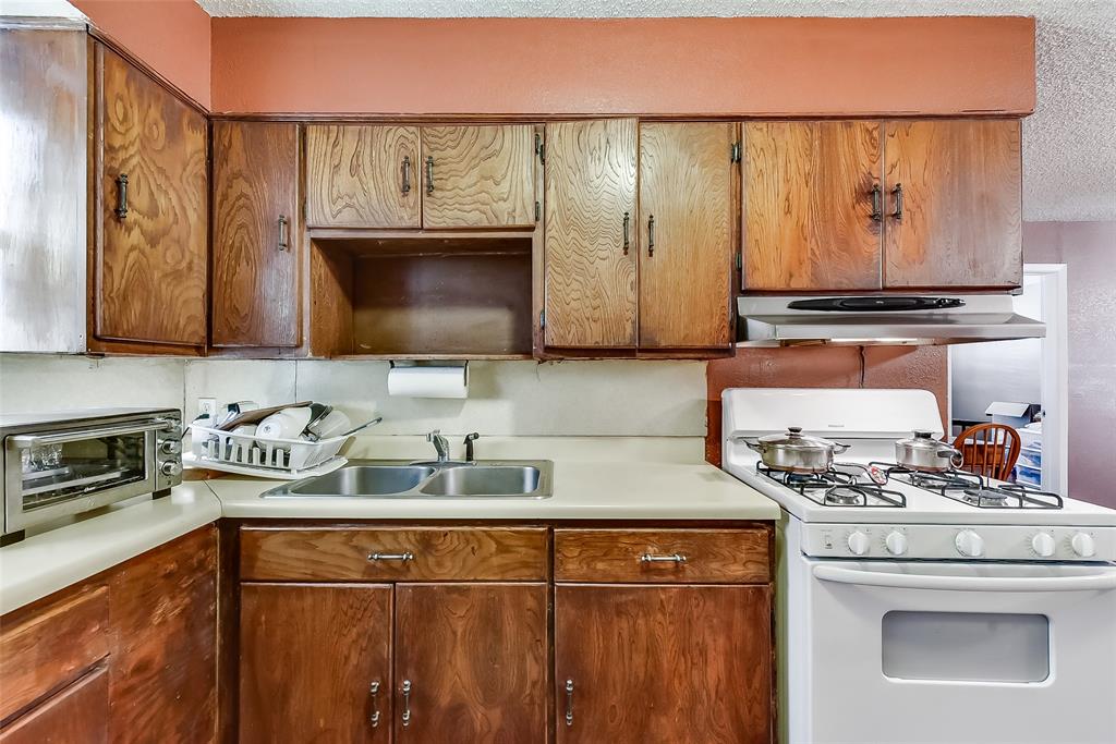 A kitchen with wooden cabinets , a stove and a sink.