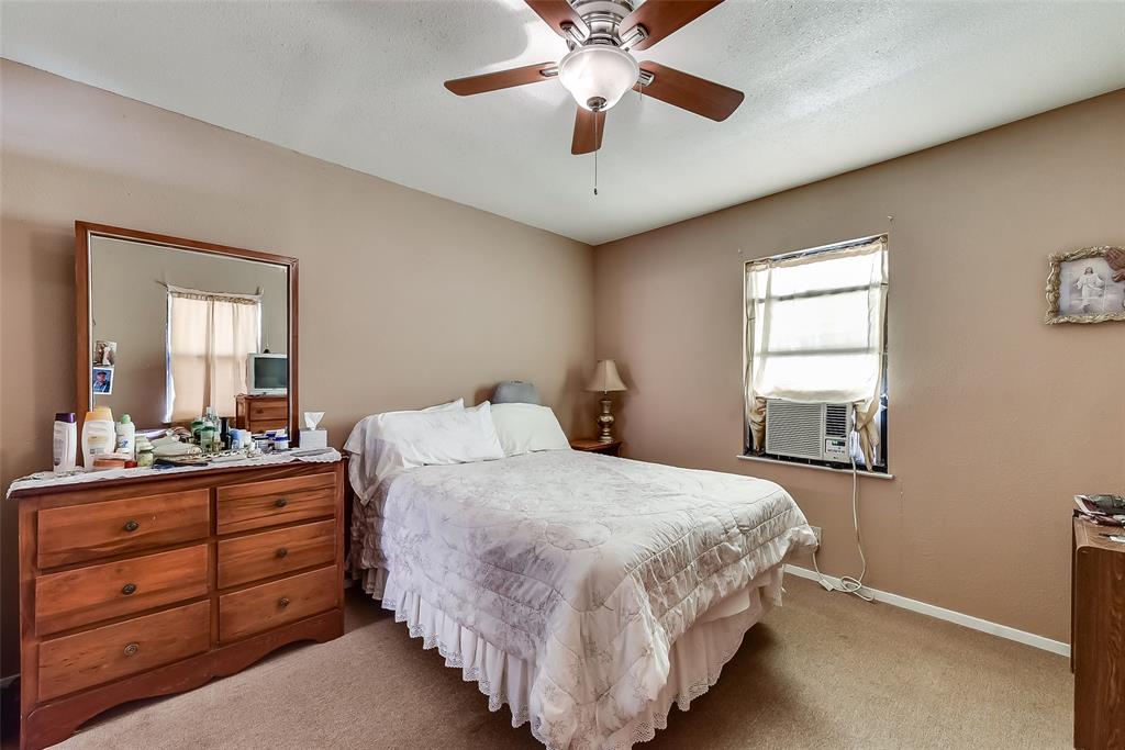 A bedroom with a bed , dresser , mirror and ceiling fan