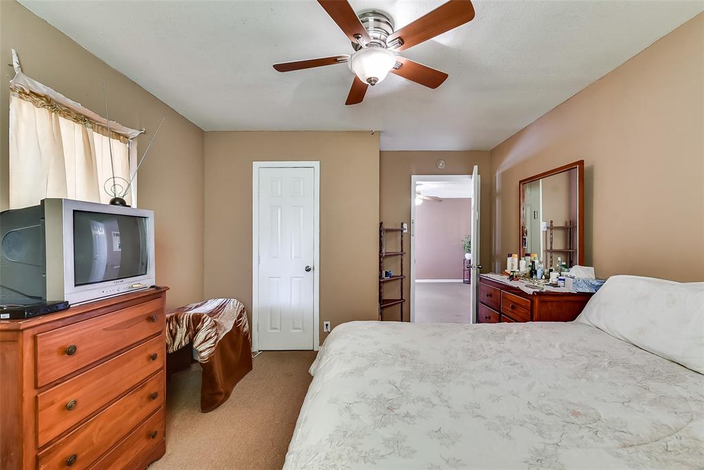 A bedroom with a bed , dresser , television and ceiling fan