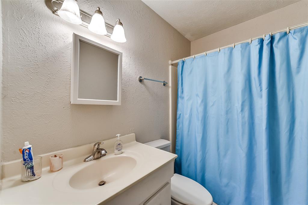 A bathroom with a blue shower curtain and a sink