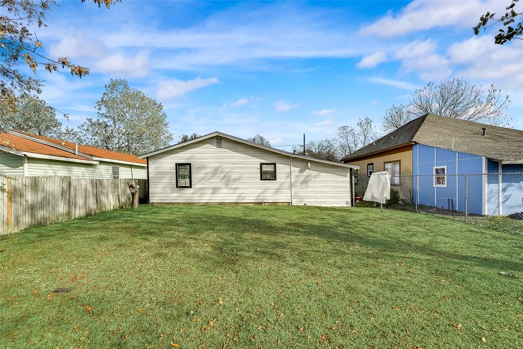 A backyard with a white house and a blue shed.
