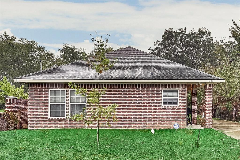 A brick house with a grassy yard in front of it