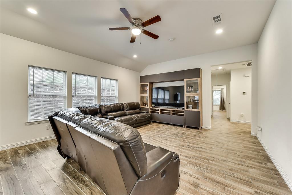 A living room with a large sectional couch and a ceiling fan