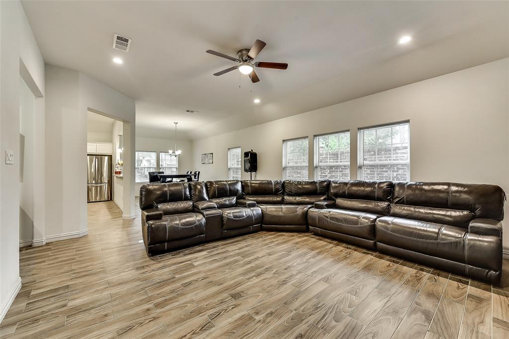 A living room with a large sectional couch and a ceiling fan.