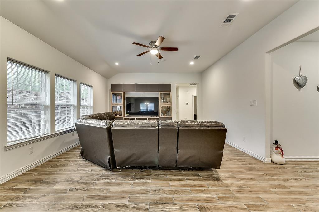 A living room with a couch , television , and ceiling fan.