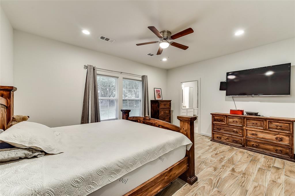 A bedroom with a bed , dresser , television and ceiling fan.