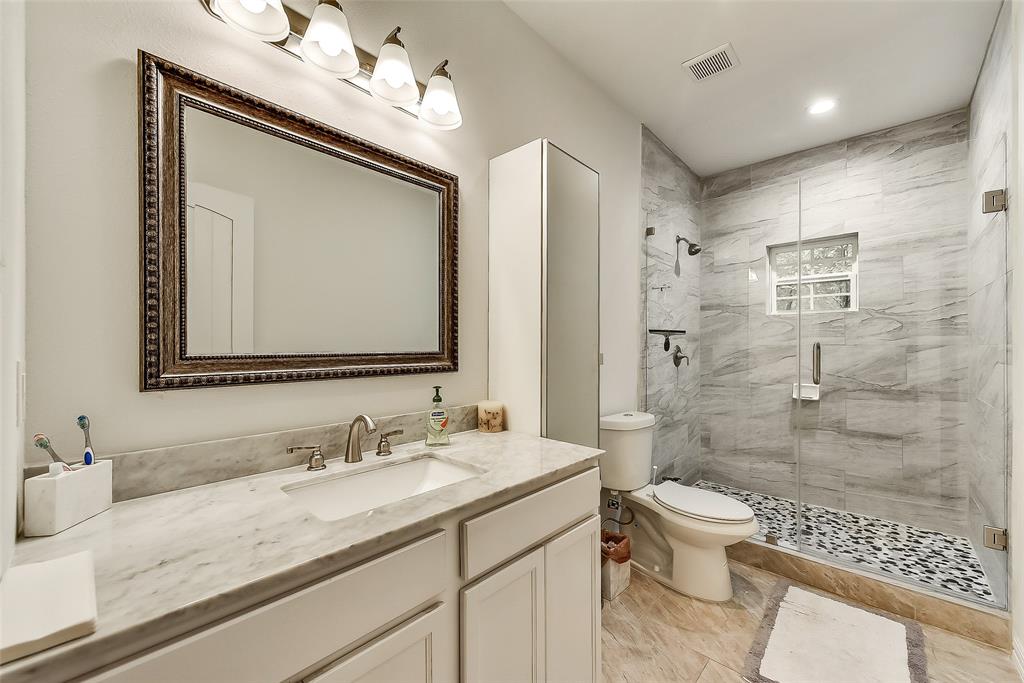 A bathroom with a sink , toilet , shower and mirror.