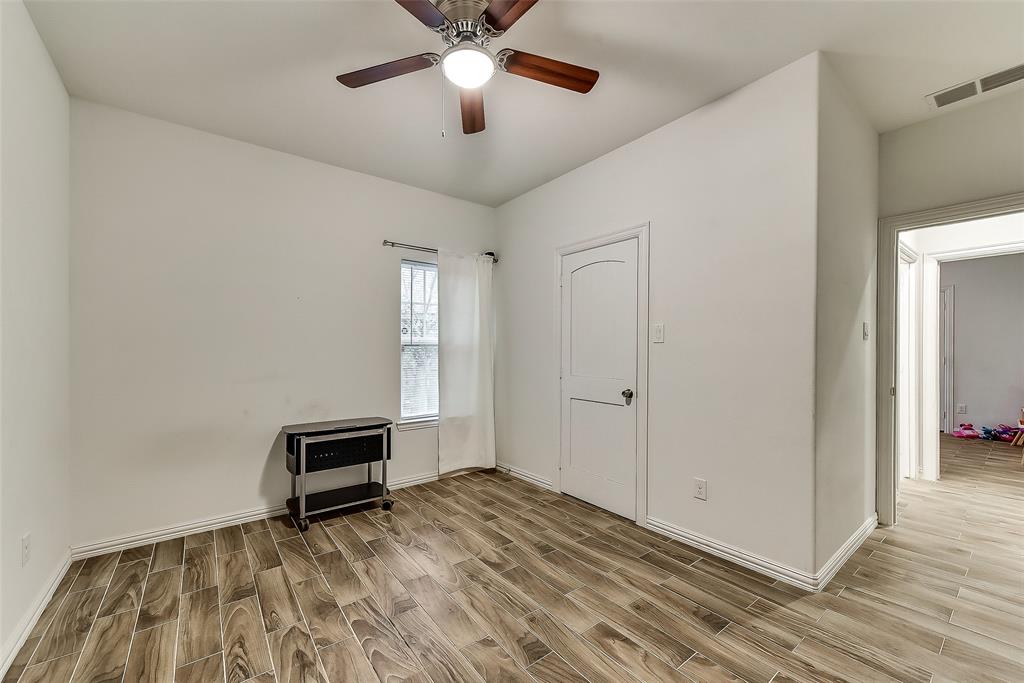 An empty room with hardwood floors and a ceiling fan.