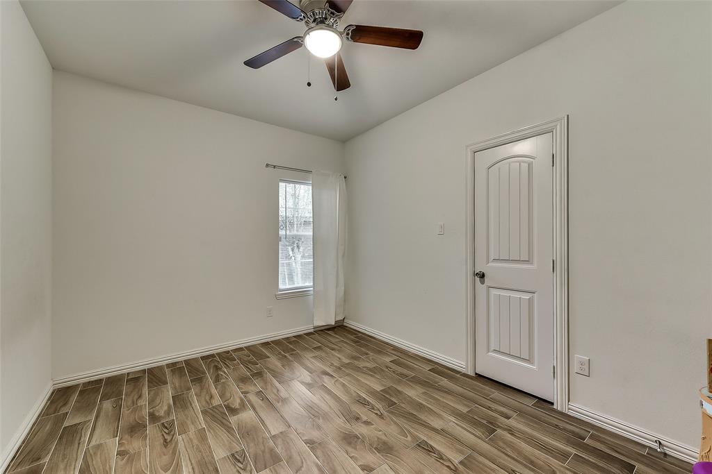 An empty bedroom with a ceiling fan and a window.