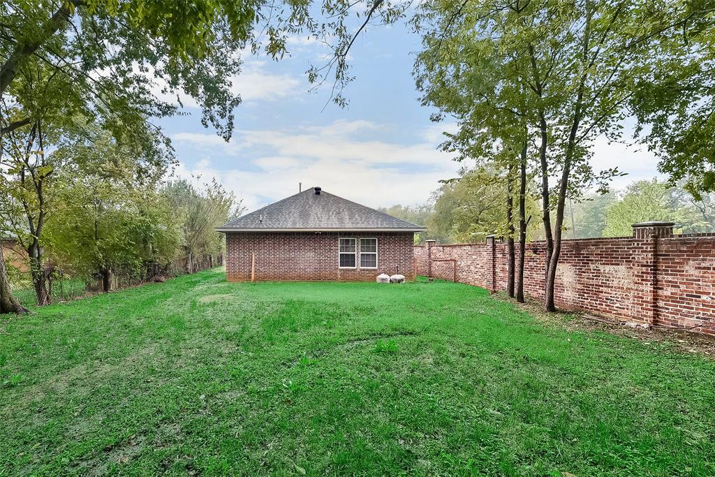 A house is sitting in the middle of a lush green field surrounded by trees.