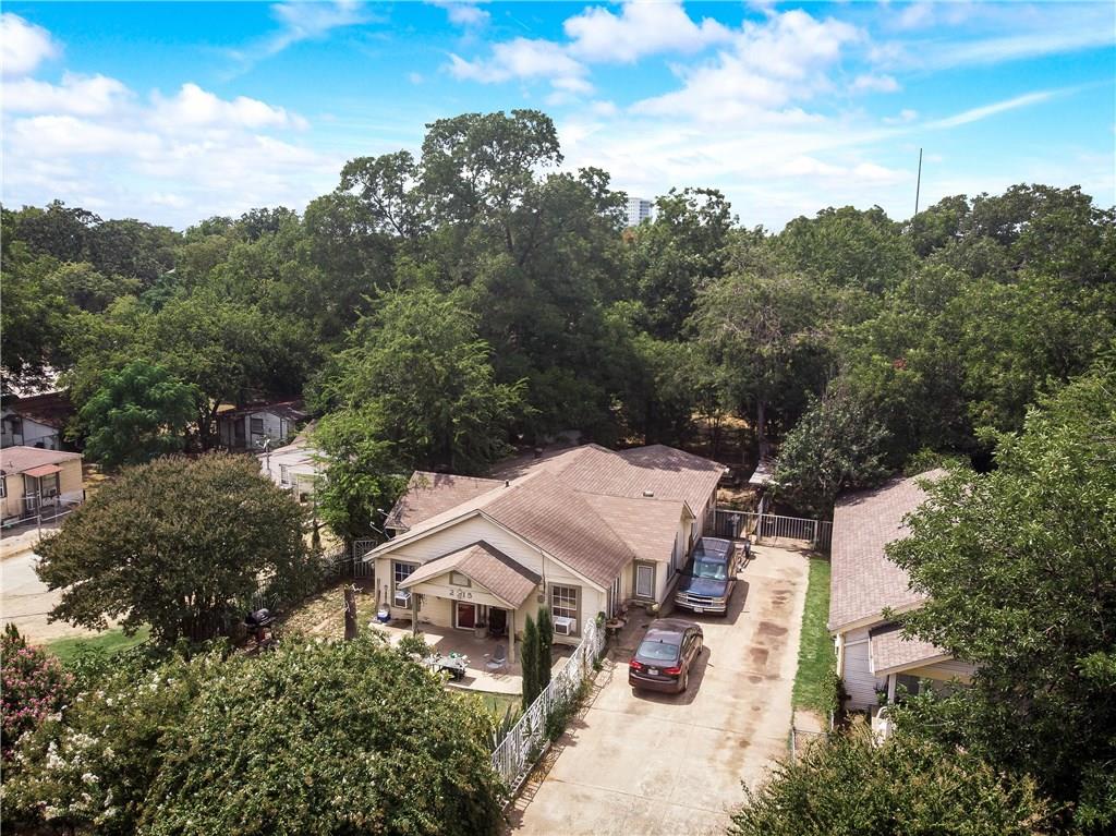 An aerial view of a house with cars parked in front of it surrounded by trees.