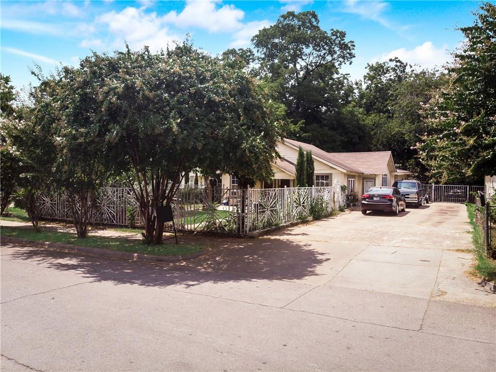 A couple of cars are parked in front of a house surrounded by trees.