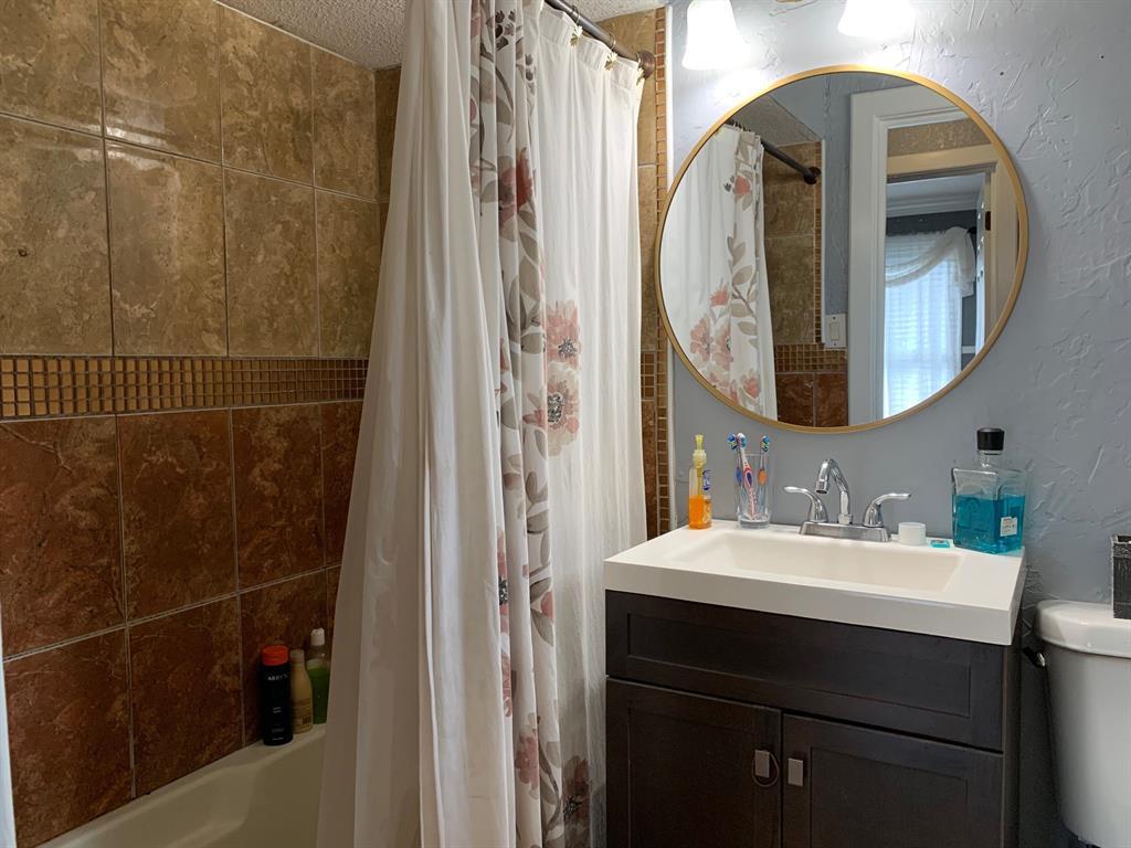 A bathroom with a sink , toilet , shower curtain and mirror.