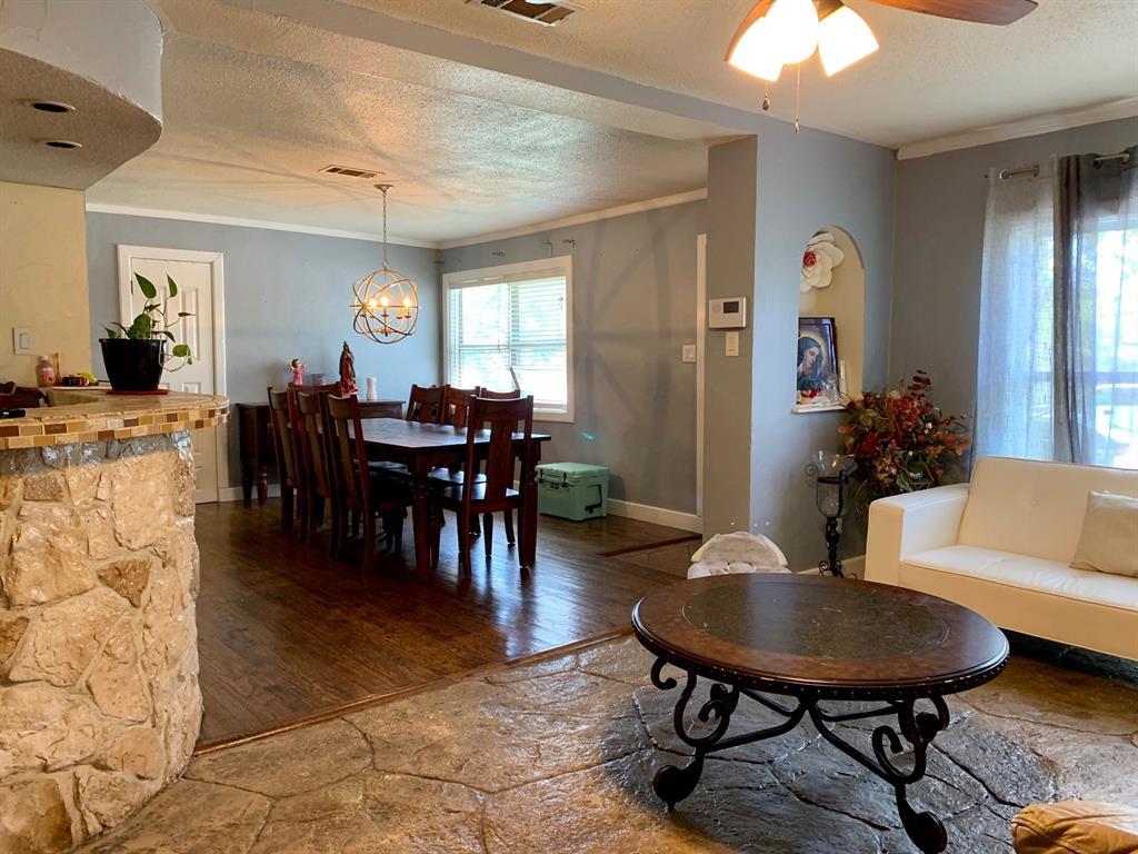 A living room with a couch , table , chairs and a ceiling fan.