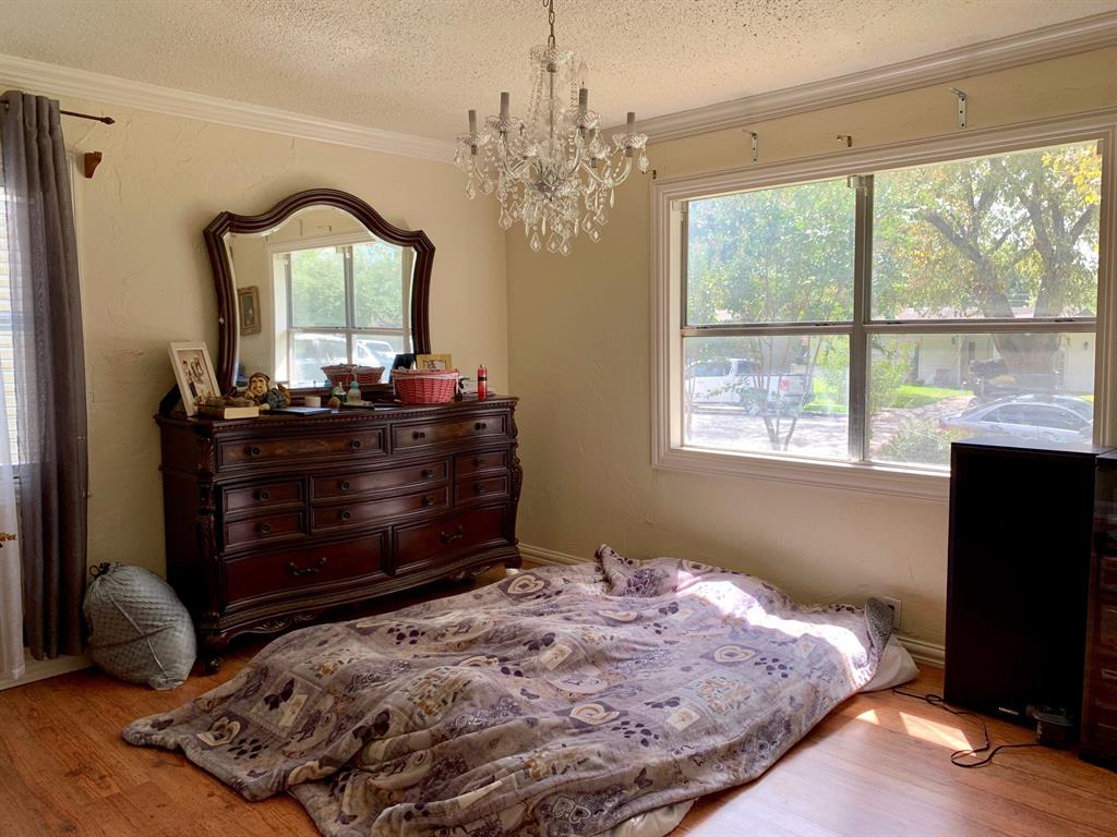 A bedroom with a bed , dresser , mirror and chandelier.