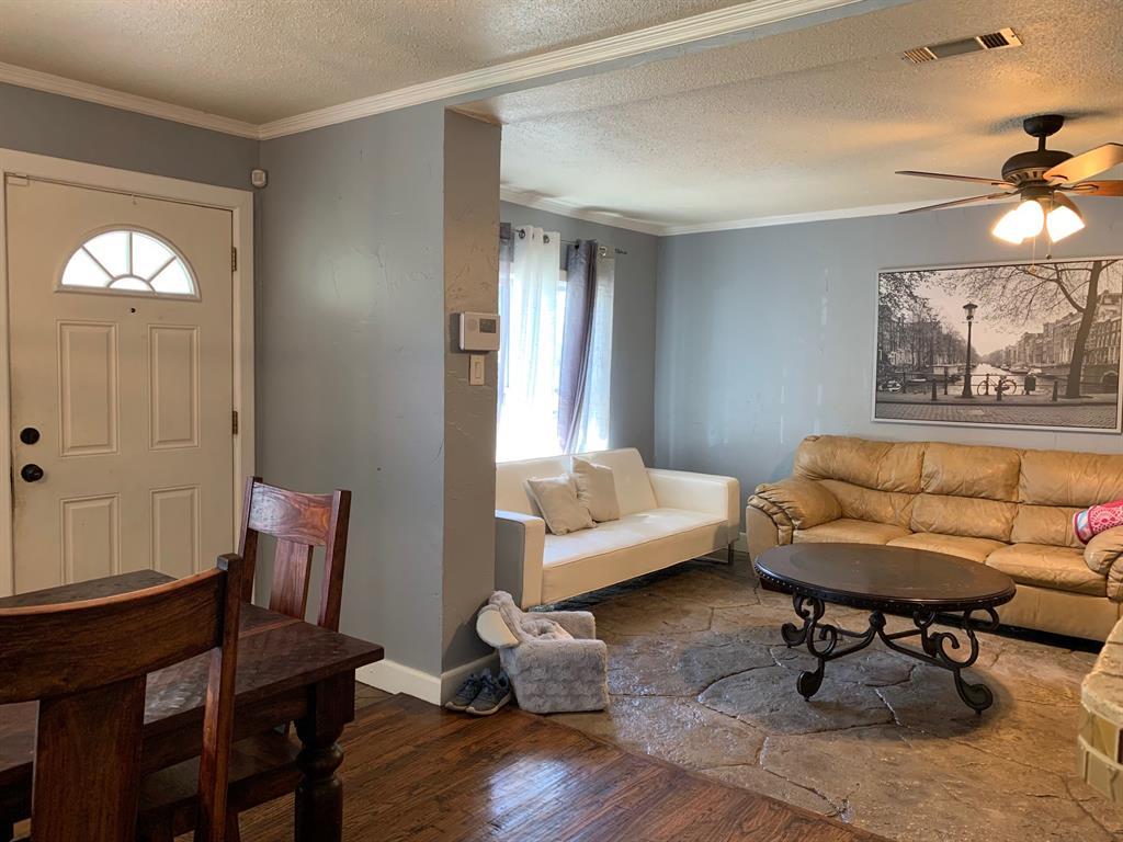 A living room with a couch , table , chairs and a ceiling fan.