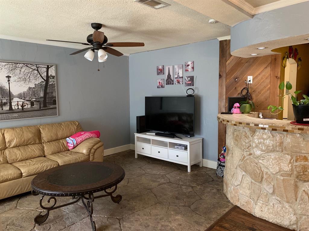 A living room with a couch , table , television and ceiling fan.