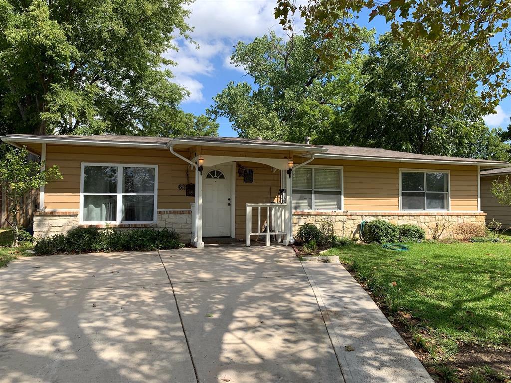 The front of a house with a concrete driveway and trees in the background.