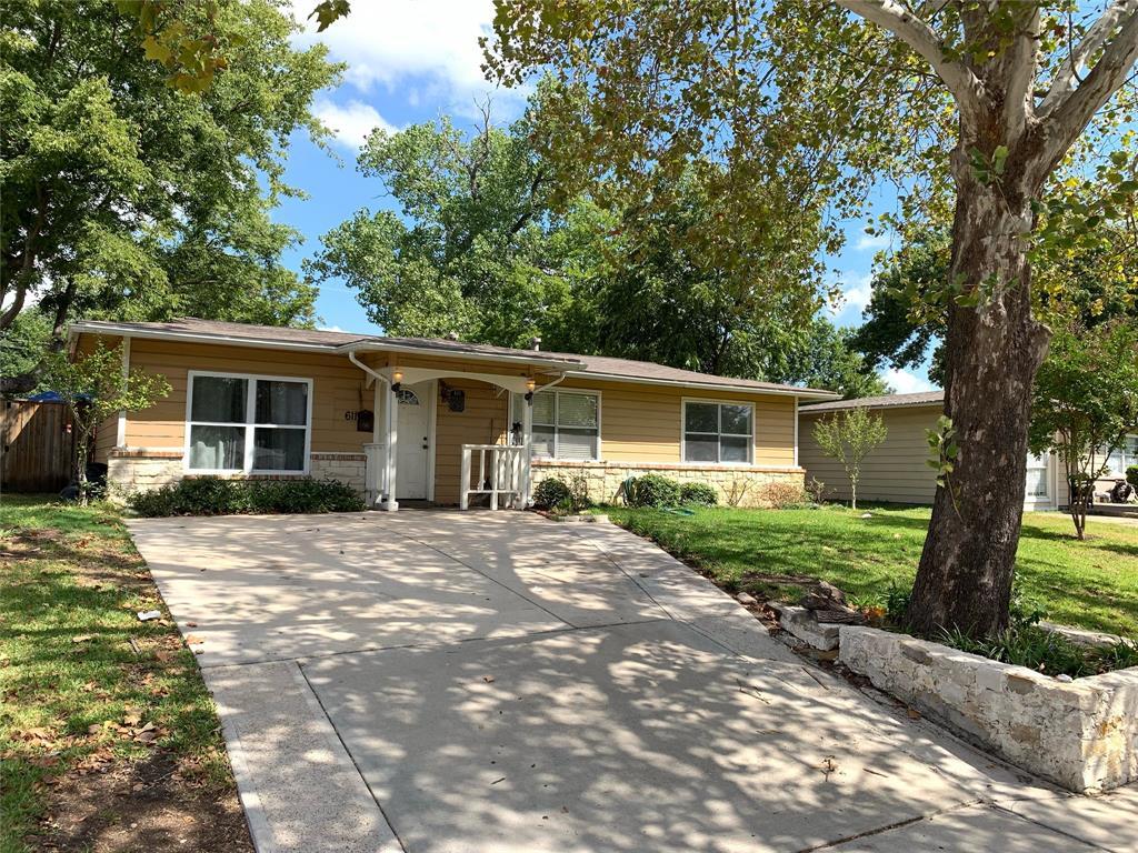 A house with a driveway and a tree in front of it.