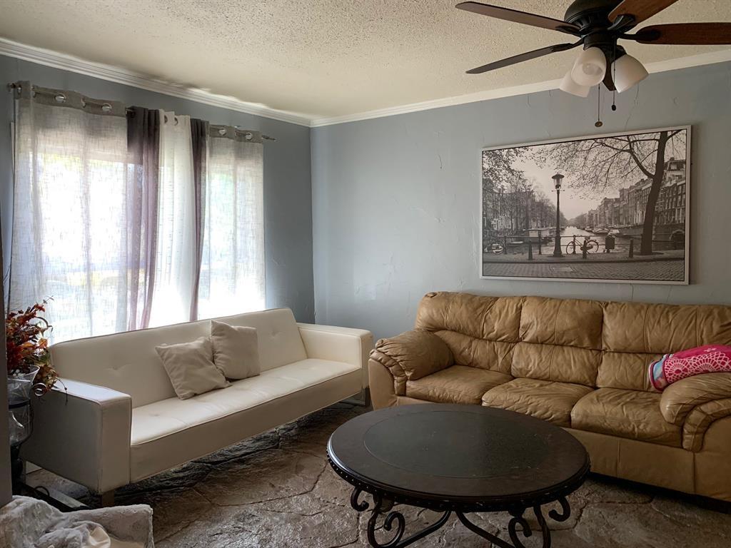 A living room with a couch , coffee table , and ceiling fan.
