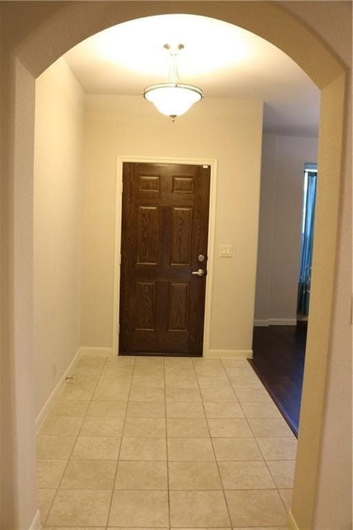 A hallway with a door and a chandelier hanging from the ceiling