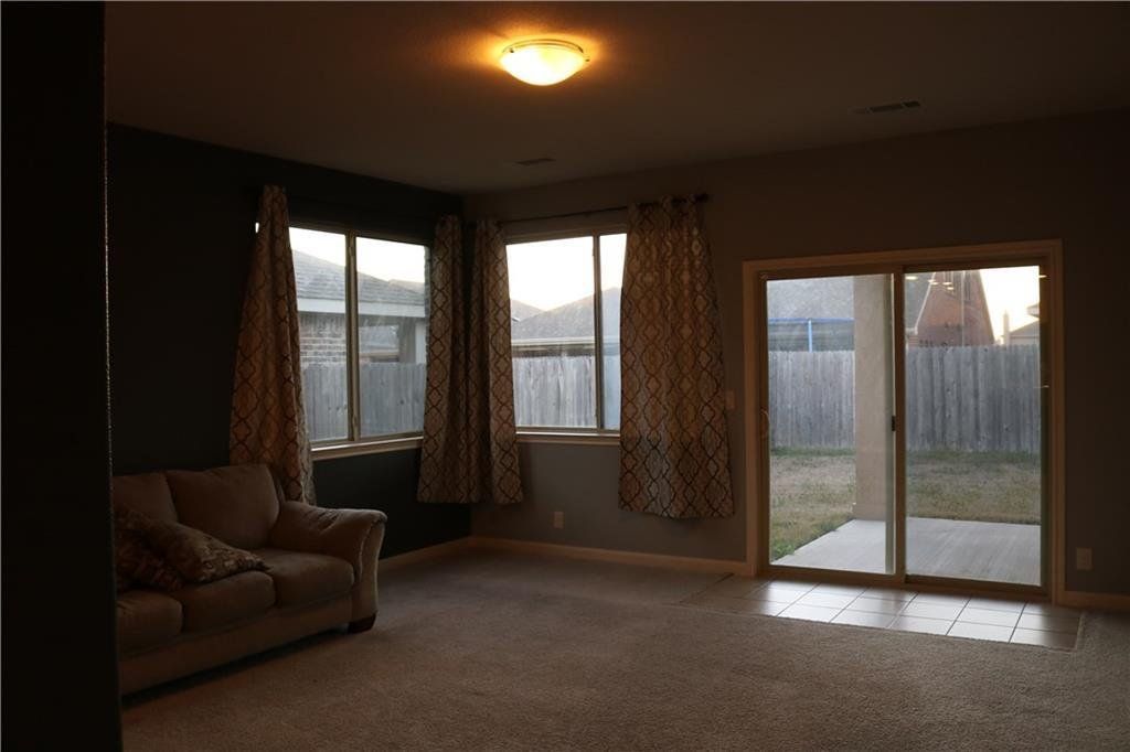 An empty living room with a couch and sliding glass doors